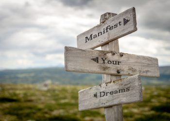 manifest your dreams text quote on wooden signpost outdoors in n